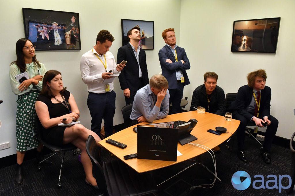 Australian Associated Press journalists look on as bureau chief Paul Osbourne (C) holds his head after being that AAP will be closing on June 26th at Parliament House in Canberra. (Mick Tsikas/AAP)