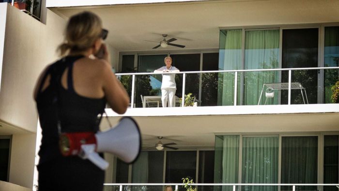 A fitness instructor uses a megaphone to help demonstrate exercises in a park to residents. Photo: ABC