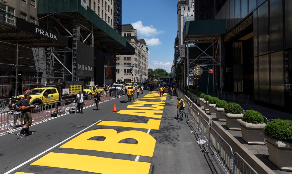 Workers put the finishing touches on lettering reading 'Black Lives Matter' on Fifth Avenue in from of Trump Tower (R) in New York, New York.  Mayor Bill de Blasio approved the public art project as a way to directly counter President Donald Trump’s dismissal of the Black Lives Matter movement.  EPA/JUSTIN LANE