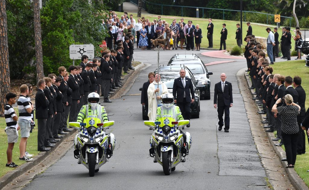 Family and friends are seen as two hearses containing the coffins of Matt Field and Kate Leadbetter are given a guard of honour by students at Iona College in Brisbane on Monday. (AAP Image/Darren England)