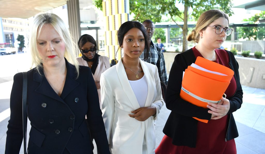 Haja Uma Timbo (centre) is seen arriving at the Brisbane Magistrates Court in Brisbane, Friday.  Timbo and Diana Lasu are being sentenced after being charged with making false statements in border declarations to avoid quarantine after travelling to Melbourne. (AAP Image/Darren England) 