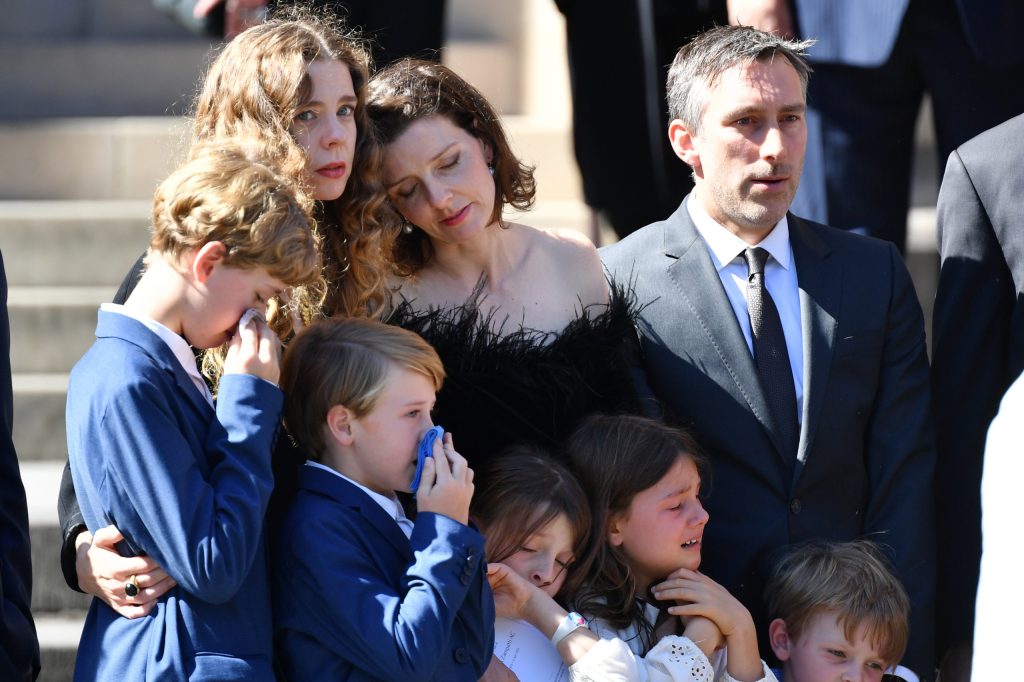 Carla Zampatti’s daughters Allegra Spender and Bianca Spender and their children look on as family members including Carla’s grandsons carry the casket from the church following a State Funeral at St Mary's Cathedral in Sydney (AAP Image/Dean Lewins)