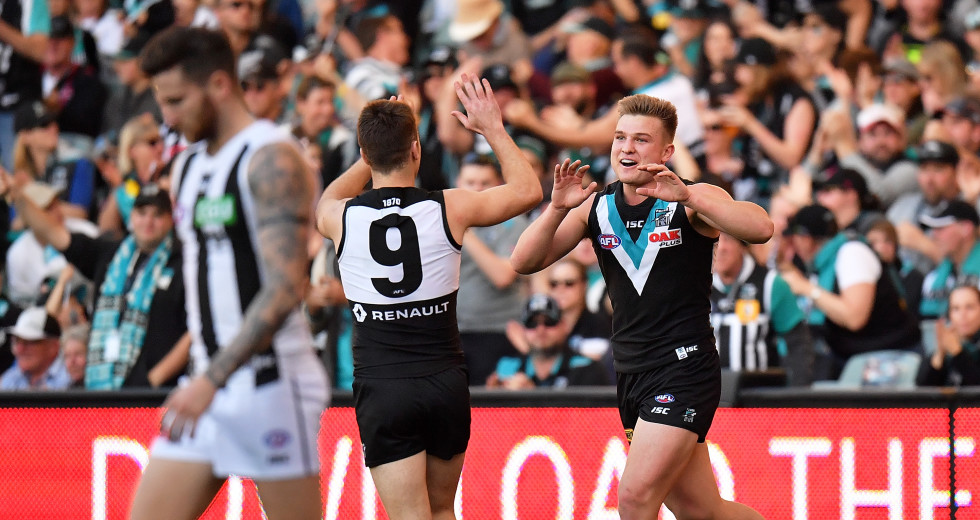 Port Adelaide players celebrate a goal in Sunday's AFL match against Collingwood at the MCG. It has been revealed that a man who tested positive as part of the latest coronavirus cluster was at the match (Image: AAP)