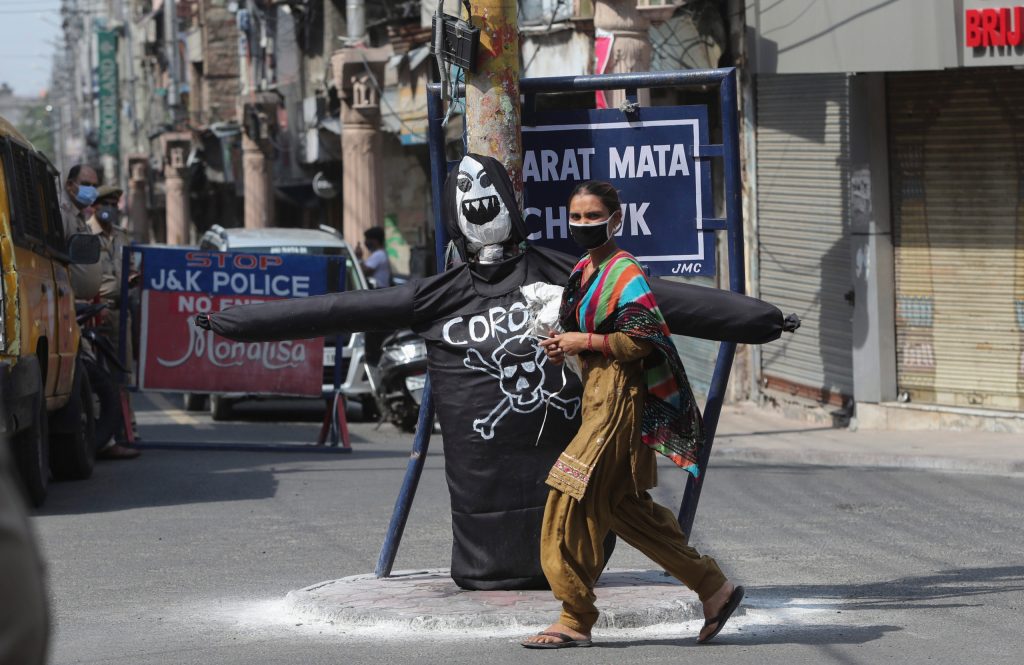 A woman wearing a face mask walks past an effigy of coronavirus at a market in Jammu, India. (AP Photo/Channi Anand)
