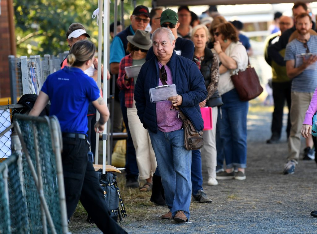 People line up to receive a coronavirus vaccination at the Rocklea Showgrounds, one of 18 hubs across the state. (AAP Image/Dan Peled) 