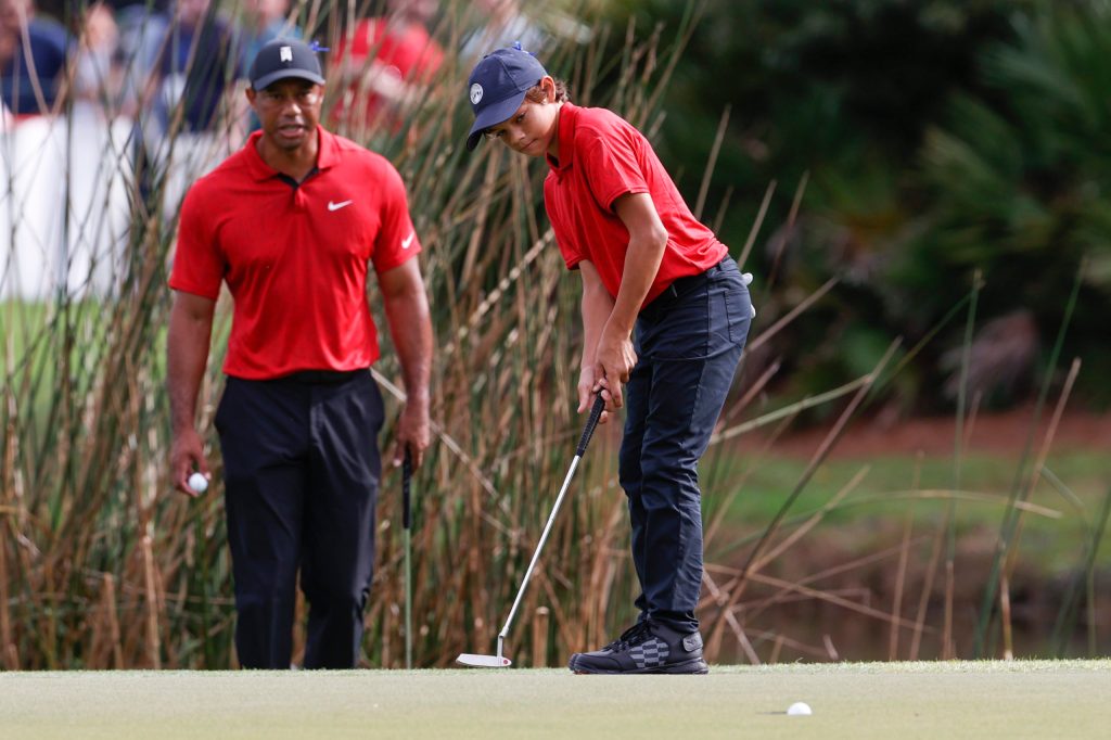 Charlie Woods sinks a putt on the second green while being watched by father Tiger Woods during the second round of the PNC Championship golf tournament in Orlando, Fla. (AP Photo/Scott Audette)