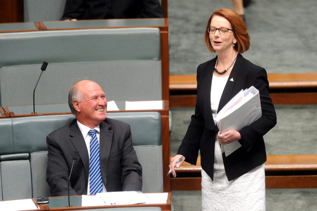 Prime Minister Julia Gillard speaks to independent MP Tony Windsor as she arrives for House of Representatives question time at Parliament House in Canberra, Tuesday, March 12, 2013. (AAP Image/Alan Porritt) 