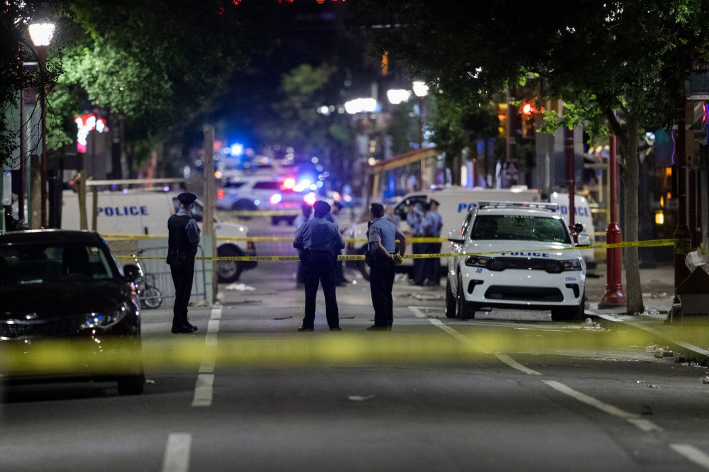 Philadelphia Police officers and detectives look over evidence at the scene of a shooting in Philadelphia, Sunday, June 5, 2022. (Charles Fox/The Philadelphia Inquirer via AP)