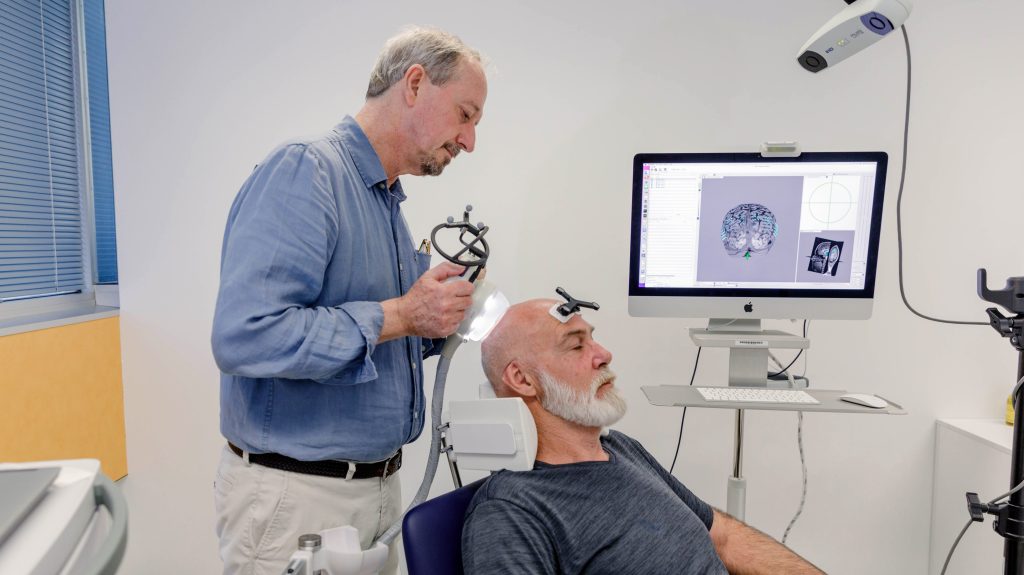 Professor Peter Nestor demonstrates the ultrasound device (please note the subject is not a participant in the trial). Image: The University of Queensland.