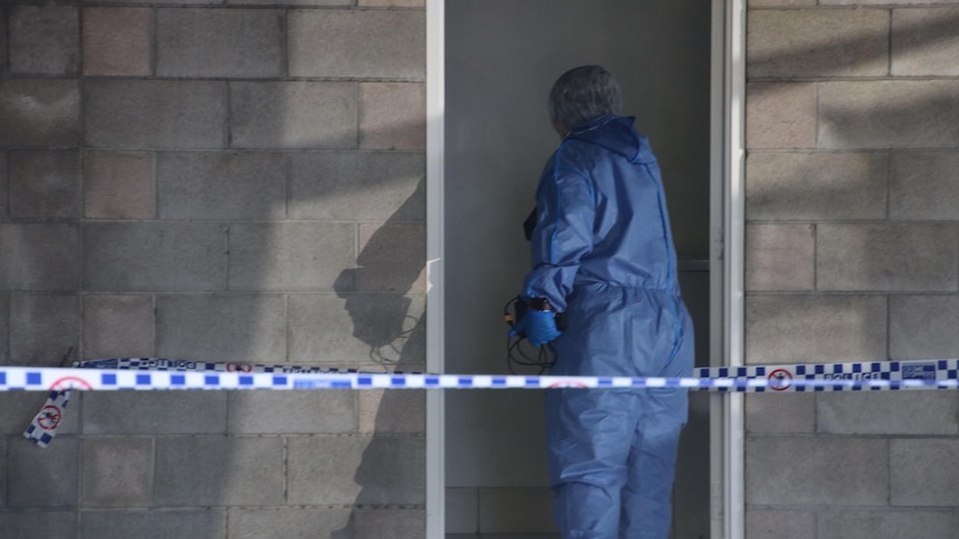 A forensic officer at the Alderley unit complex where the body was found. (ABC News: Jemima Burt)