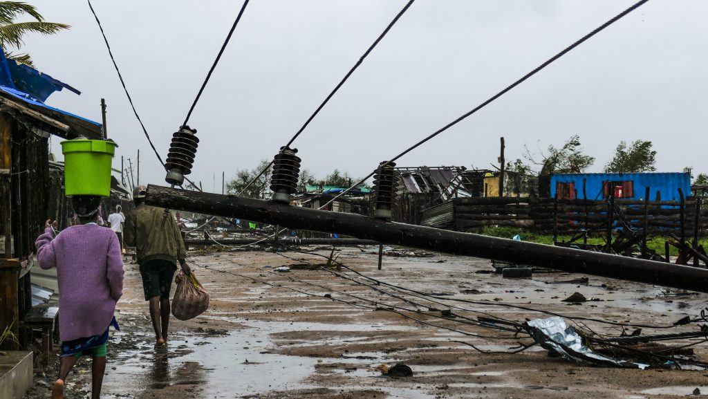 People walk on a flooded street near Quelimane, as the storm Freddy hits Mozambique, 12 March 2023. . This is one of the longest lasting storms ever, after it formed at the beginning of February in the Asian seas, crossing the entire Indian Ocean to the east African coast.  EPA/ANDRE CATUEIRA