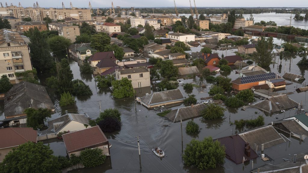 People ride on a rubber boat in a flooded neighborhood in Kherson, Ukraine.(AP Photo/Roman Hrytsyna)