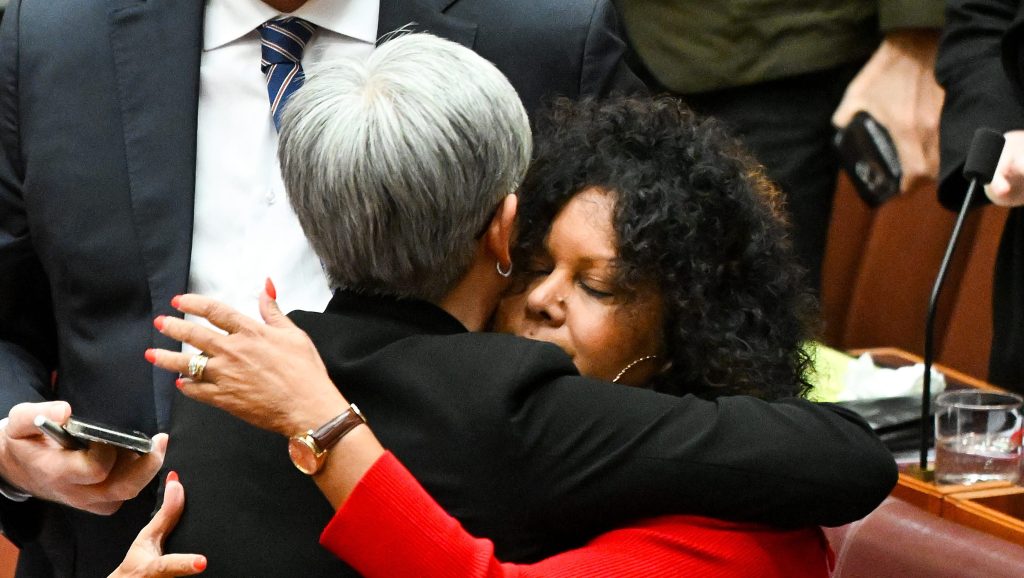 The Leader of the Government in the Senate Penny Wong embraces Senator Malarndirri McCarthy after the passing of the Voice to Parliament in the Senate chamber at Parliament House, in Canberra, Monday, June 19, 2023. (AAP Image/Lukas Coch)