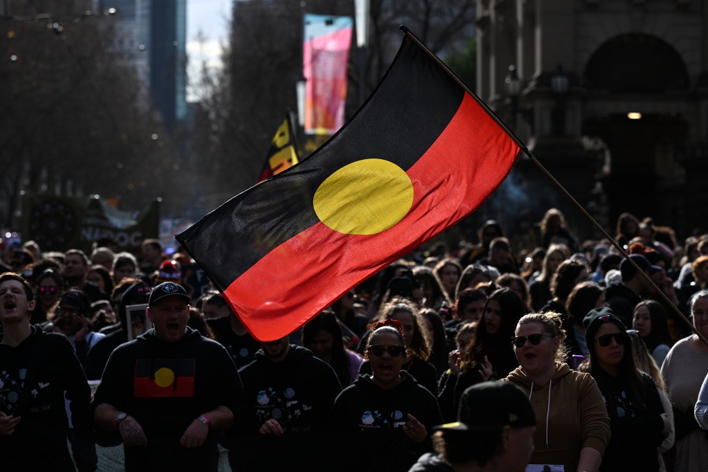 A person holds up the indigenous flag during the annual Victorian NAIDOC march, in Melbourne, Friday, July 7, 2023. (AAP Image/James Ross) NO ARCHIVING