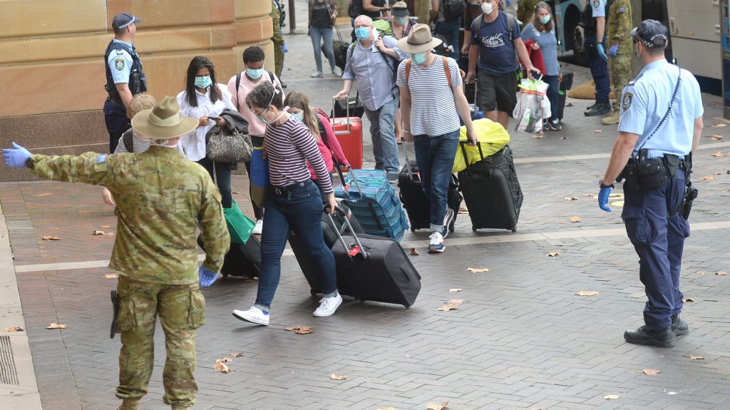 Returning overseas travellers are ushered into the InterContinental Hotel for the beginning of their 14-day imposed quarantine in Sydney, Sunday, March 29, 2020. (AAP Image/Jeremy Piper) 
