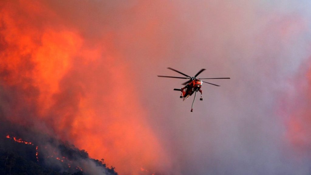 A firefighter helicopter battles a blaze at Tawonga Gap in Victoria, (AAP Image/Chris Hocking) NO ARCHIVING