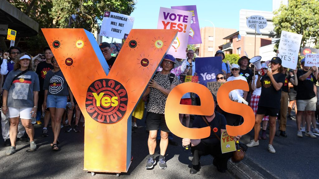 People hold up a Yes sign during a walk for the Yes vote event in Sydney. (AAP Image/Steve Markham)