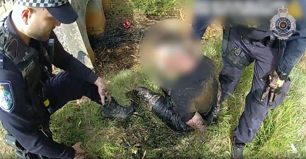 An image taken from video shows Queensland Police officers arresting a man after he allegedly fled the scene of a crash that killed an elderly woman north of Brisbane - one of 600,000 offences in the state last year. (AAP Image/Supplied by Queensland Police Service)