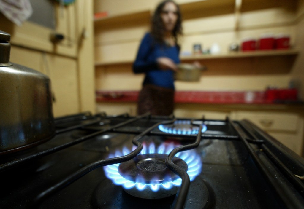 A Chilean woman holds a pot as she prepares a meal in her kitchen, in Santiago March 27, 2004. Argentina's restriction on exports of surplus natural gas will not immediately affect supplies to Chile, which depends on its neighbor for more than 90 percent of its natural gas needs, but could in the future, a government official said on Friday. Some 35 percent of Chile's electricity comes from natural-gas burning plants, and Chilean power companies' shares dropped on the stock exchange on Friday after Argentina announced some restrictions on exports. NTRES REUTERS/Carlos Barria  CB/HB
