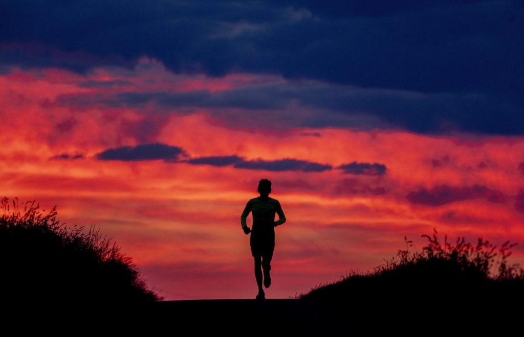 A man runs on a small road in the outskirts of Frankfurt, Germany, before sunrise on Tuesday, May 31, 2022. (AP Photo/Michael Probst)