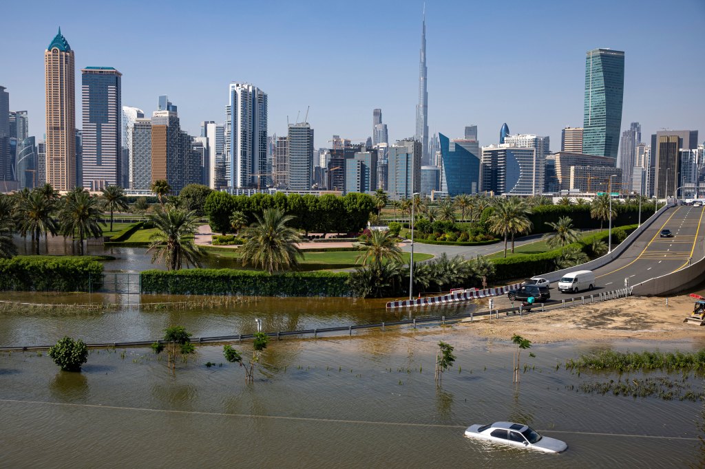 An abandoned vehicle stands in floodwater caused by heavy rain with the Burj Khalifa, the world's tallest building, seen on the background, in Dubai, United Arab Emirates, Thursday, April 18, 2024. The United Arab Emirates attempted to dry out Thursday from the heaviest rain the desert nation has ever recorded, a deluge that flooded out Dubai International Airport and disrupted flights through the world's busiest airfield for international travel. (AP Photo/Christopher Pike)