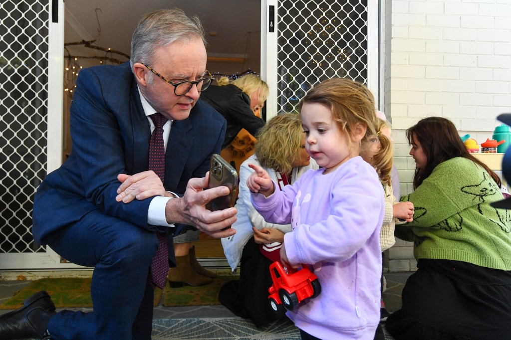 Prime Minister Anthony Albanese shows a child a photo of his dog at Goodstart Early Learning Red Hill in Brisbane, Wednesday, July 17, 2024. (AAP Image/Jono Searle) NO ARCHIVING